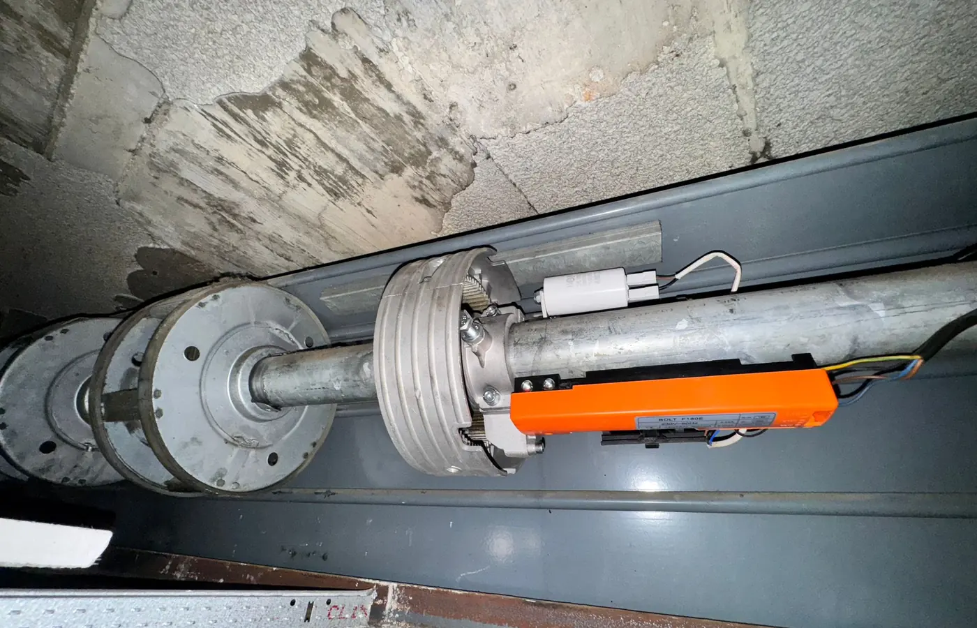 Motor central montado en el eje de una persiana metálica, con su freno y el cableado ya conectado